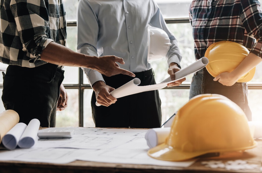 Bauingenieur Teams treffen zusammen arbeiten tragen Arbeiter Helme hardhat auf der Baustelle in der modernen Stadt. Vorarbeiter Industrie Projektleiter Ingenieur Teamarbeit. Asiatische Industrie professionelles Team